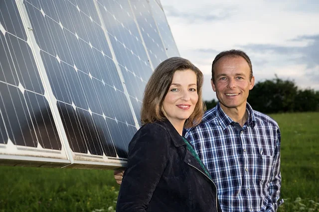 Ein Mann und eine Frau stehen lächend vor einer Photovoltaik-Analage